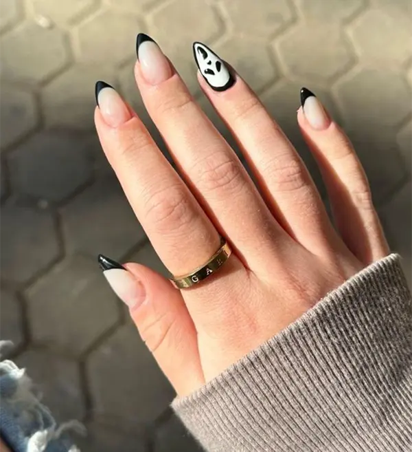 Halloween nails with black French tips and one nail featuring a "Scream" mask design